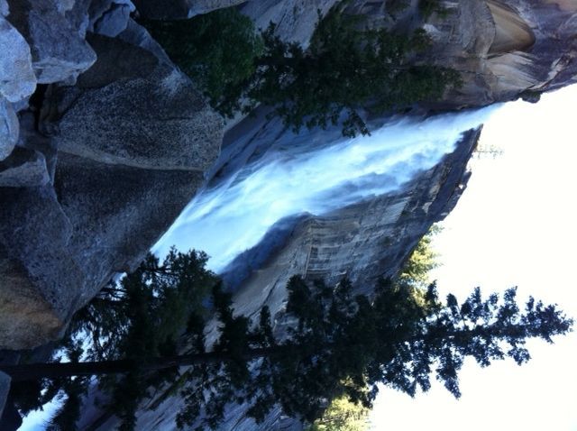 Waterfall cascading down a rocky cliff, trees in the foreground.