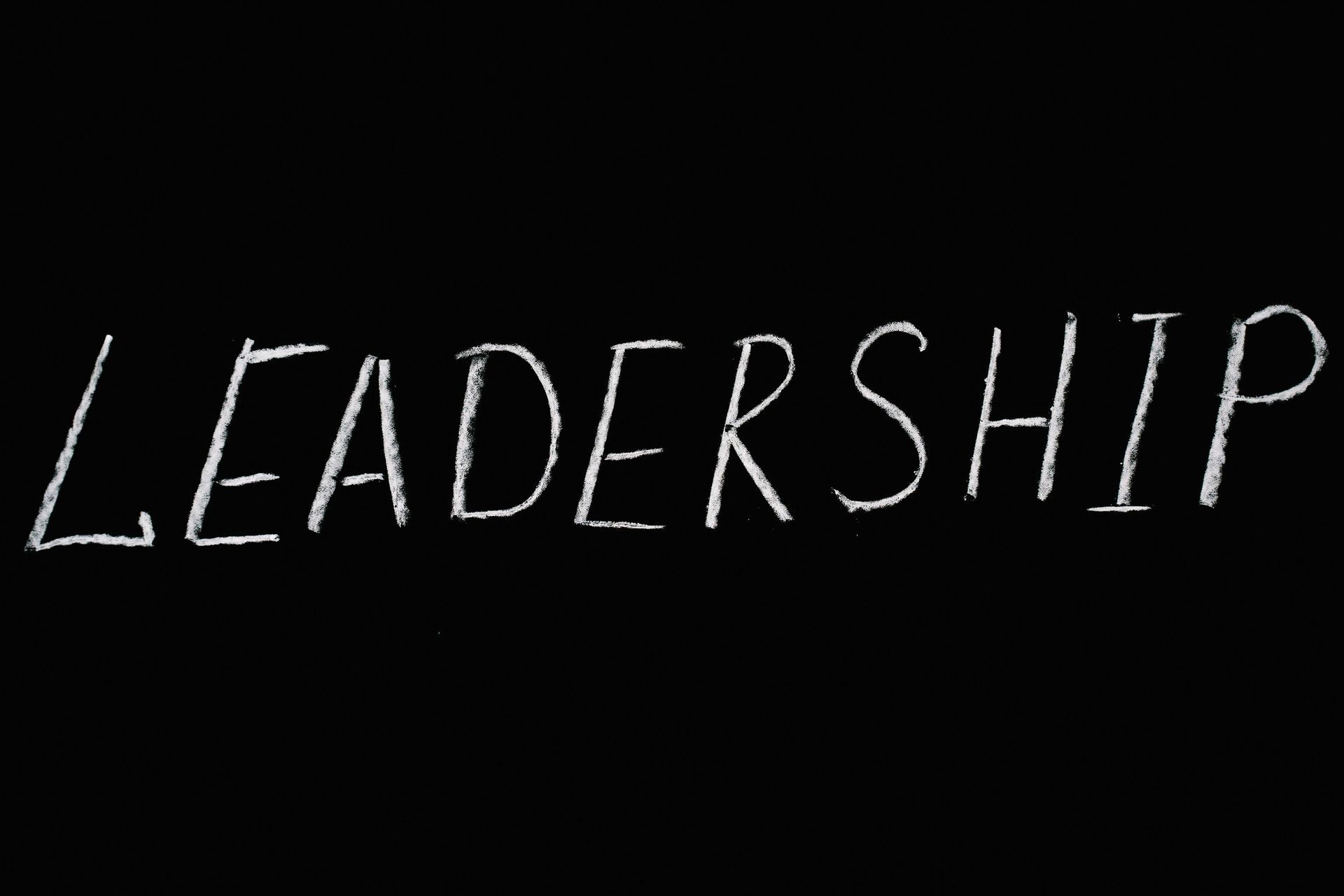 White handwritten word “LEADERSHIP” on a black background.