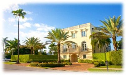 A large, light-colored building with palm trees in front; sunny day.