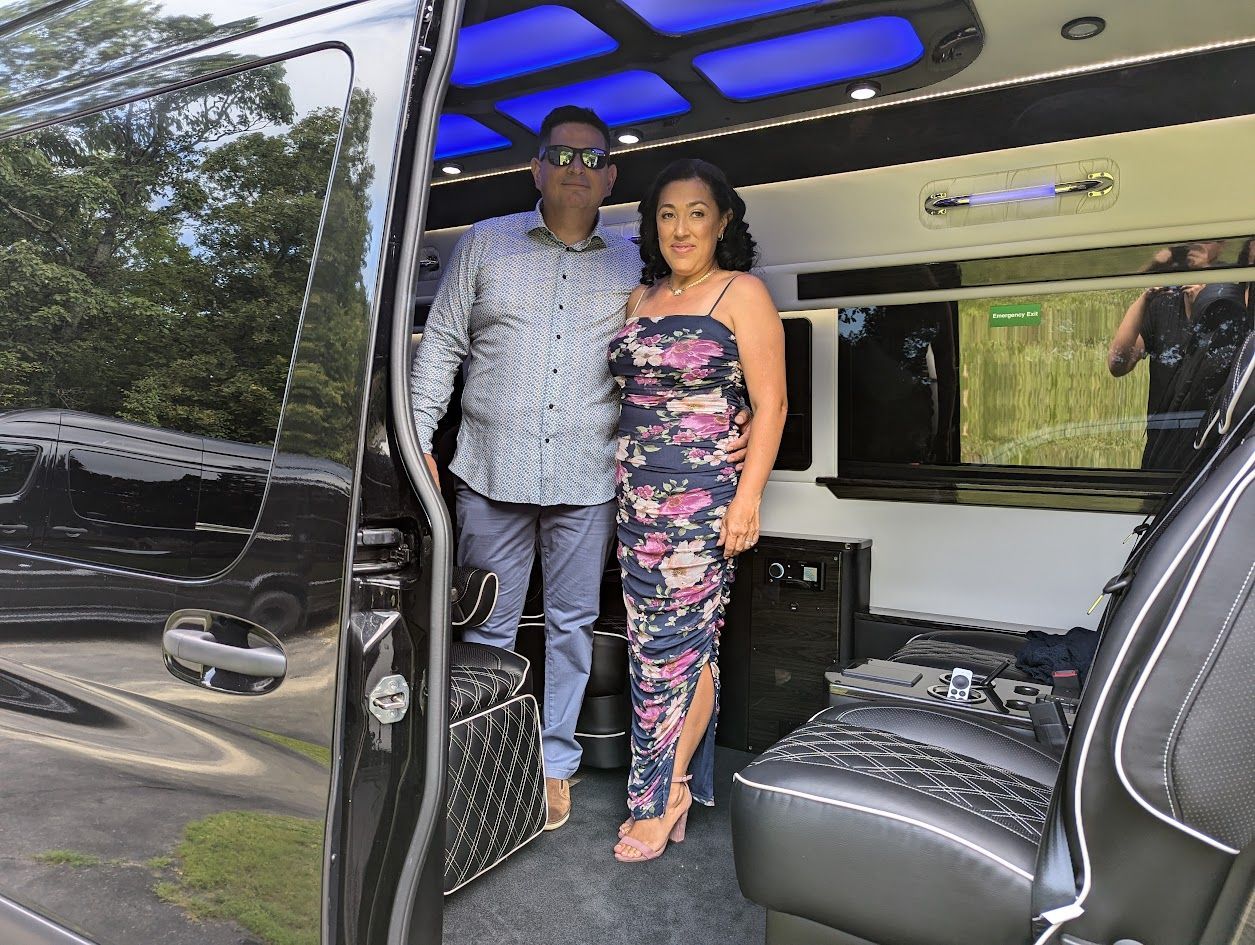 A man and a woman are standing in the doorway of a van.