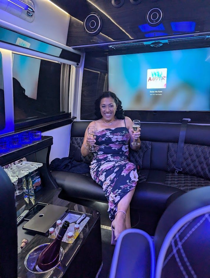 A woman is sitting on a couch in a van holding a glass of champagne.