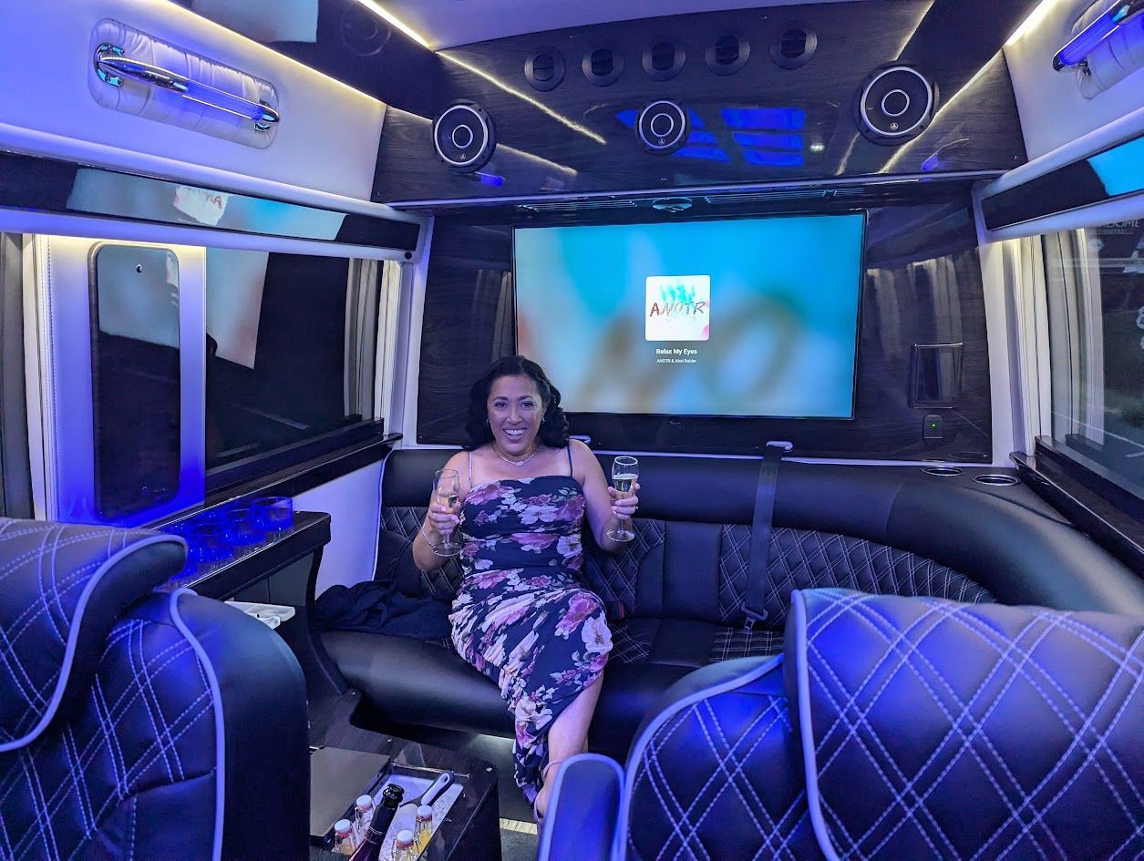A woman is sitting on a couch in a limousine holding a glass of wine.
