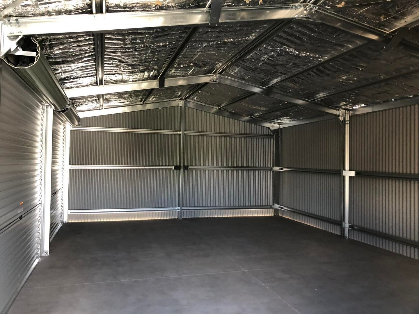 An empty garage with a metal roof and a concrete floor.