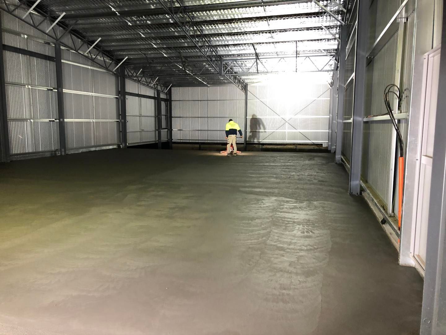 A man is standing on a concrete floor in a warehouse.