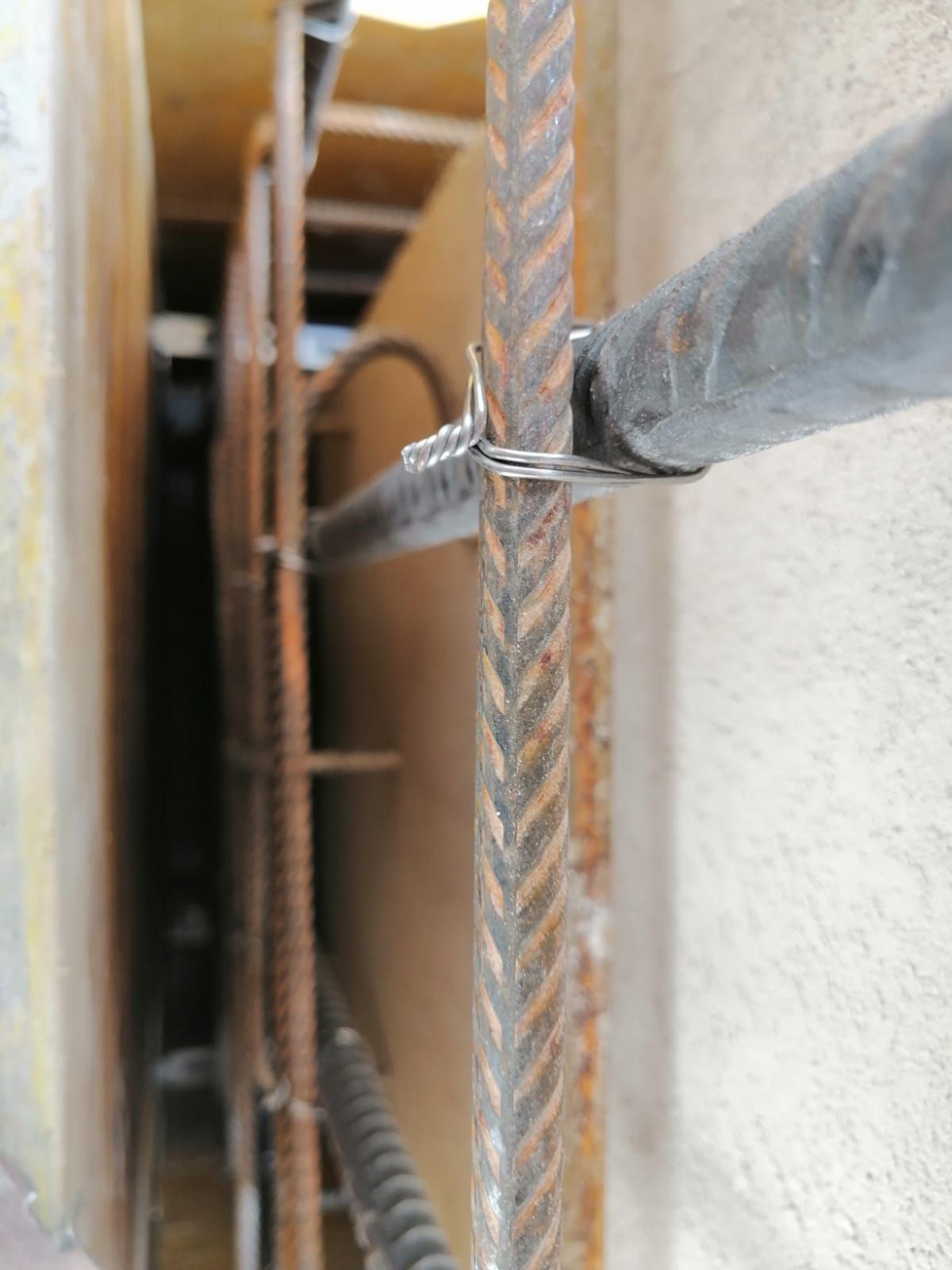 Primo piano di barre di rinforzo legate insieme con filo metallico all'interno di una cassaforma in legno per calcestruzzo.