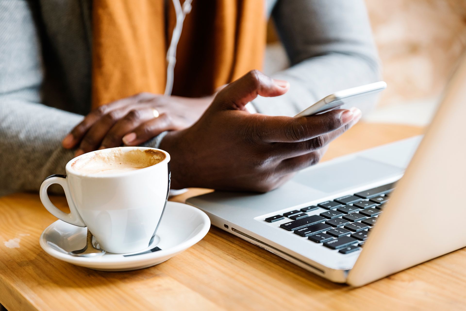 A person is sitting at a table with a cup of coffee and a laptop.
