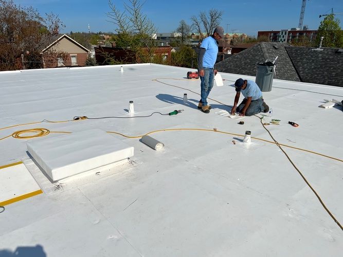 Two men are working on a white roof.