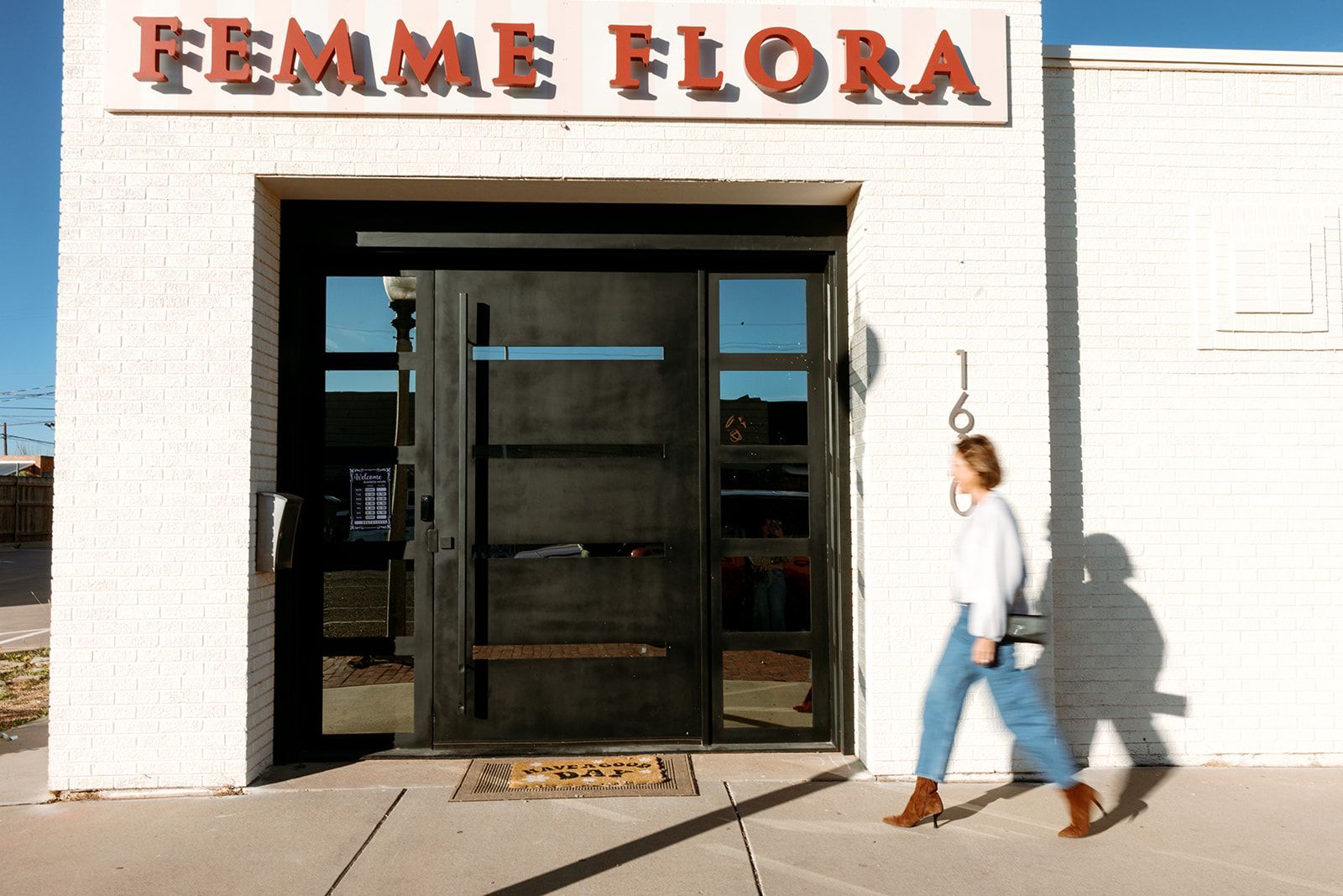 Storefront with “FEMME FLORA” sign and a person walking past the entrance.
