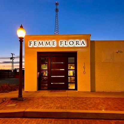 Storefront of Feme Flora at dusk, with warm yellow walls and a lit streetlamp outside.