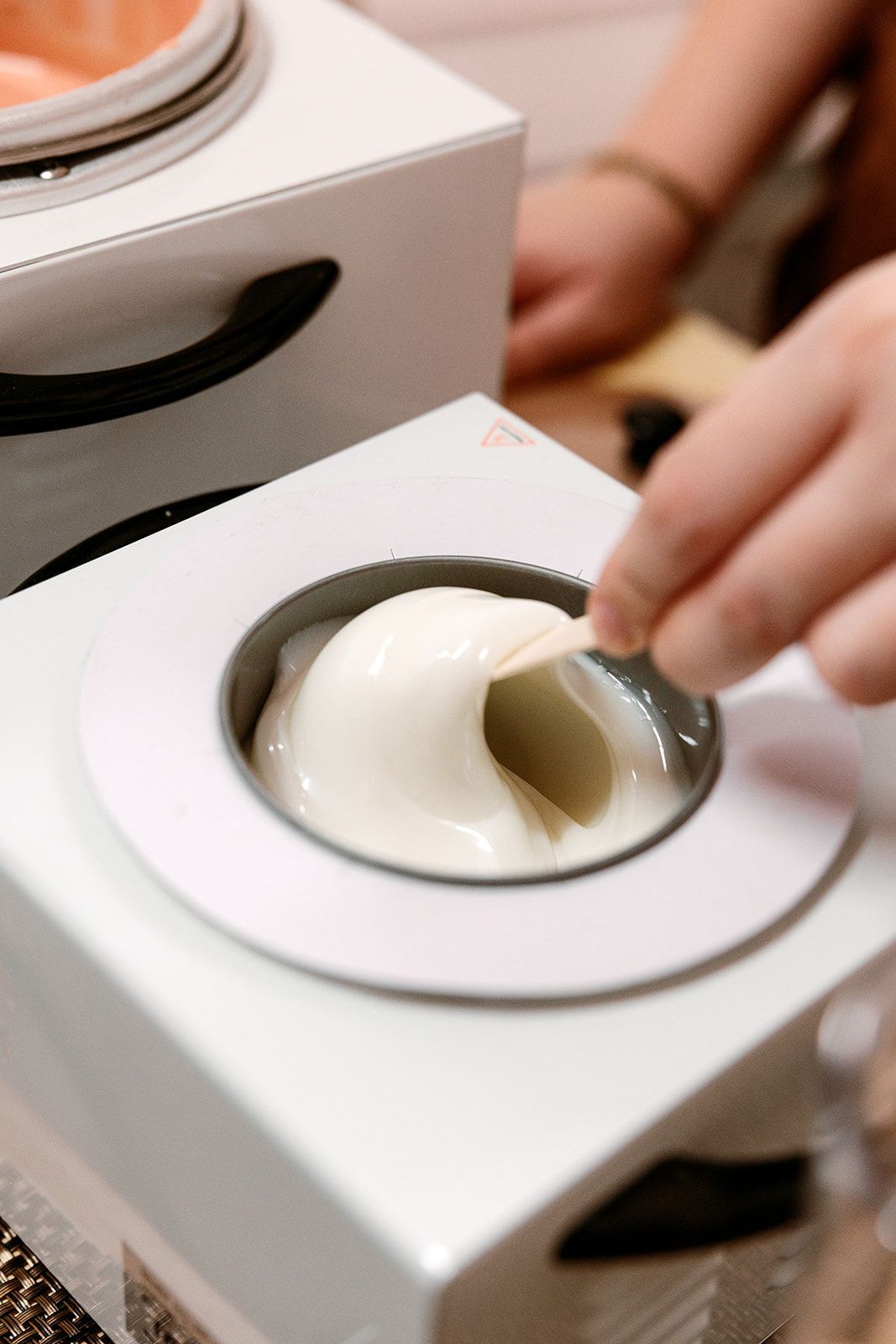 Hand scooping white gelato from a round container in a white display case