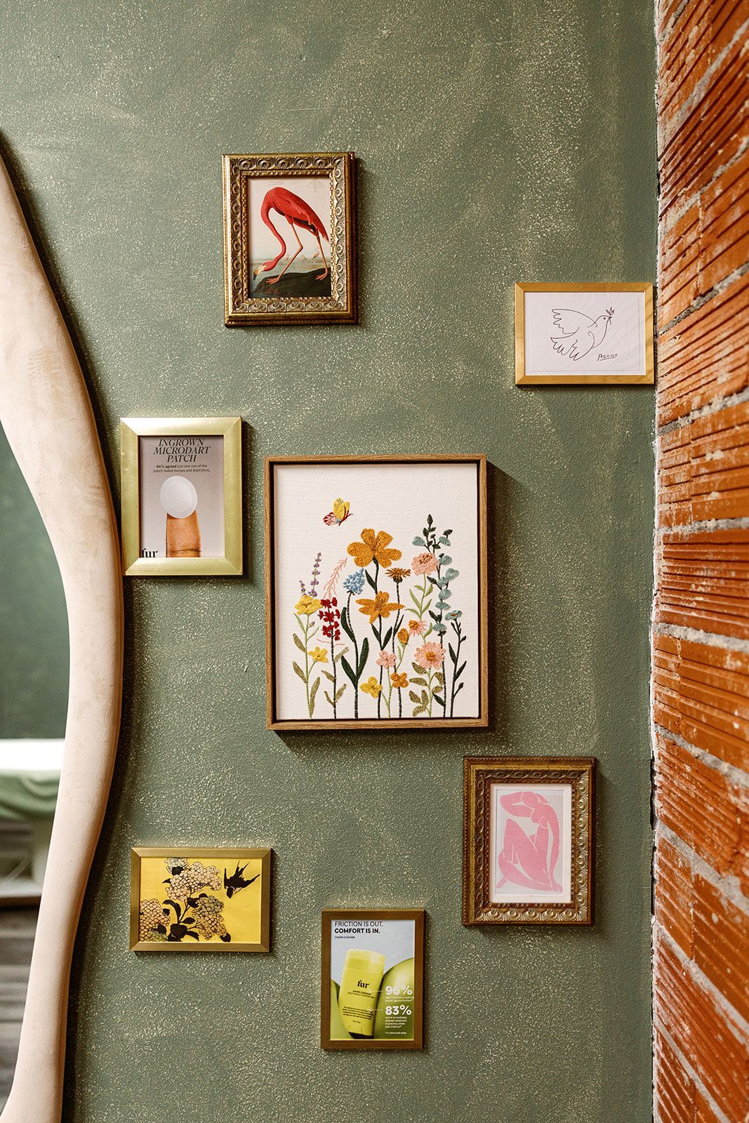 Framed floral artwork gallery wall with assorted small prints on green and brick walls