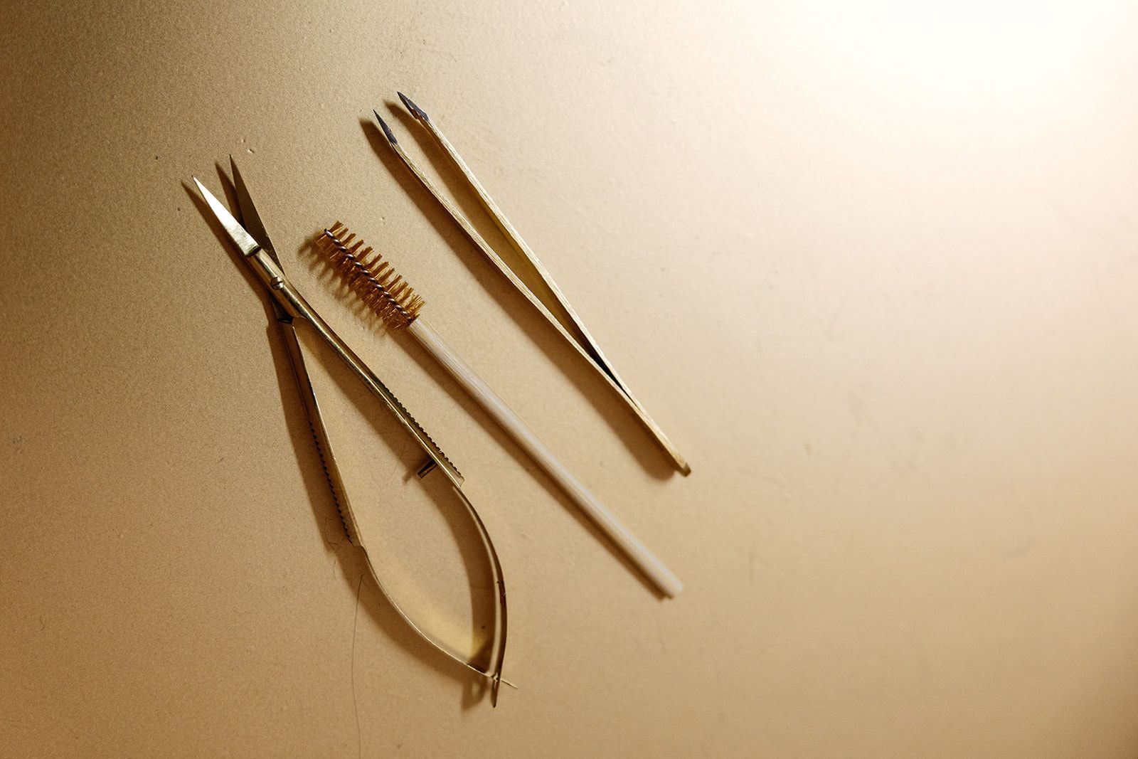 Three wooden hair sticks and a small brush on a beige surface