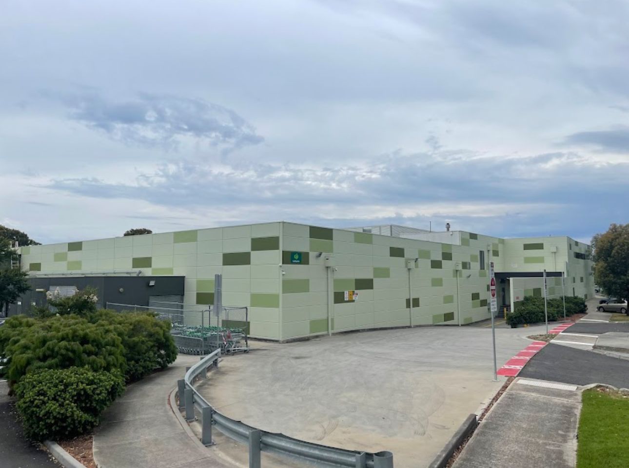 A large, light green building with darker green rectangular accents under a cloudy sky.