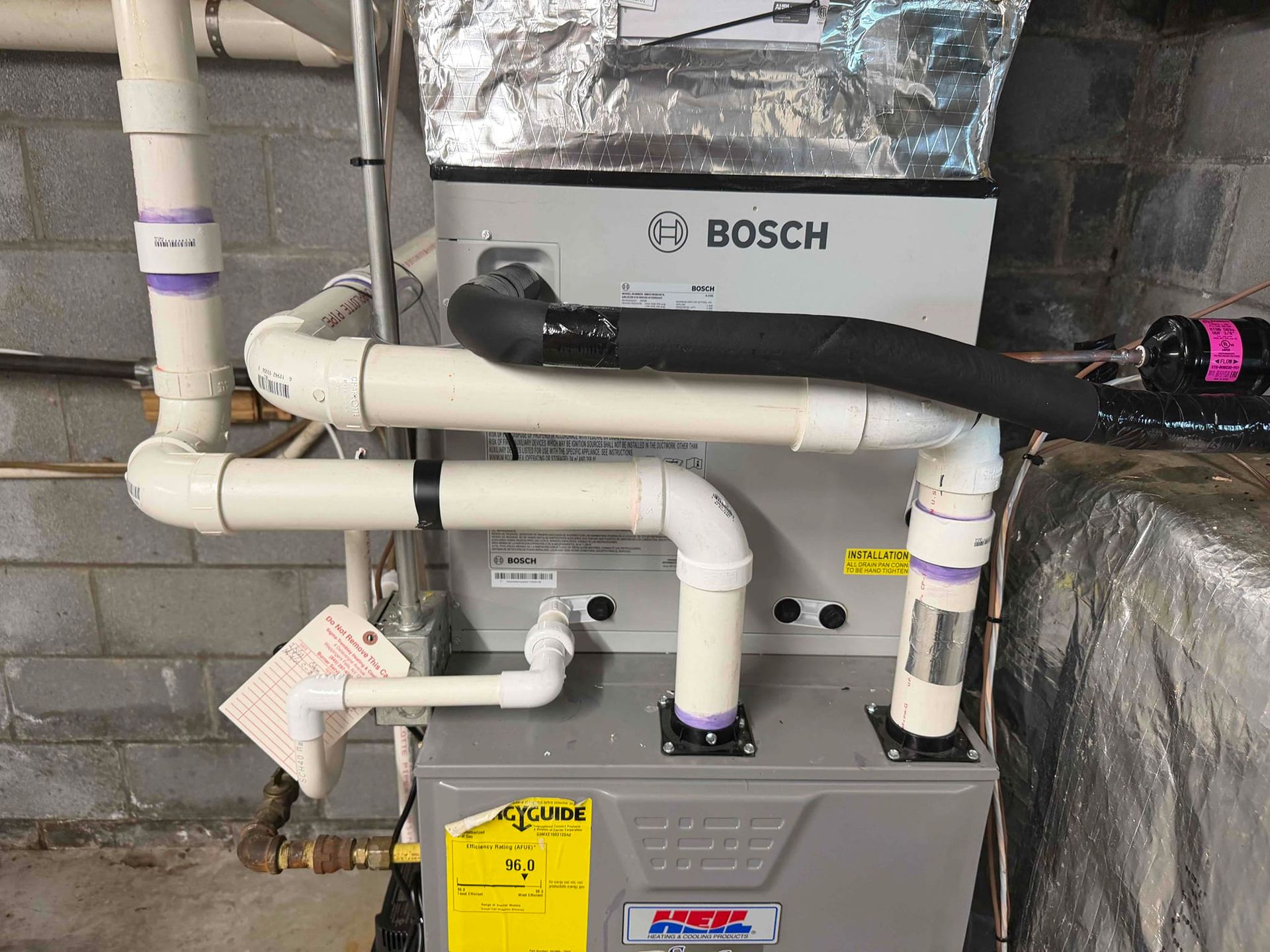 Bosch furnace with white PVC pipes and ductwork in a basement utility area