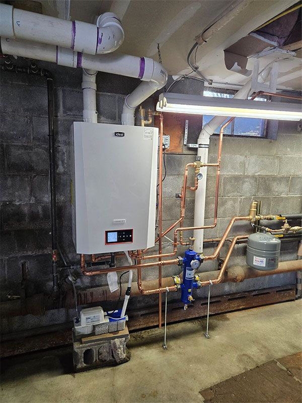 Basement mechanical room with a white wall-mounted boiler, copper piping, and PVC venting on a concrete floor