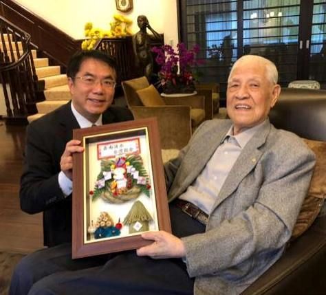 兩名男子正在擺姿勢拍照，其中一人手裡拿著相框