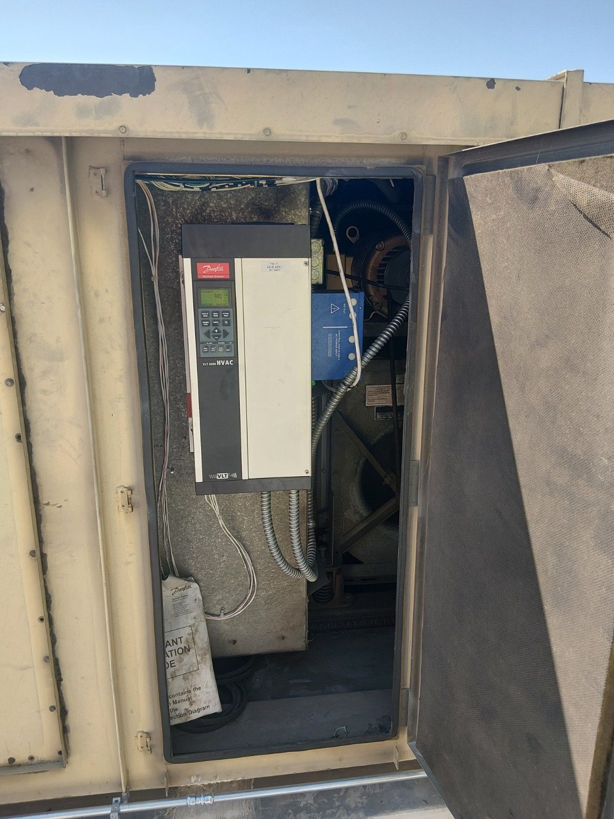 A beige industrial HVAC unit with its side door open, revealing an electronic control drive mounted inside.