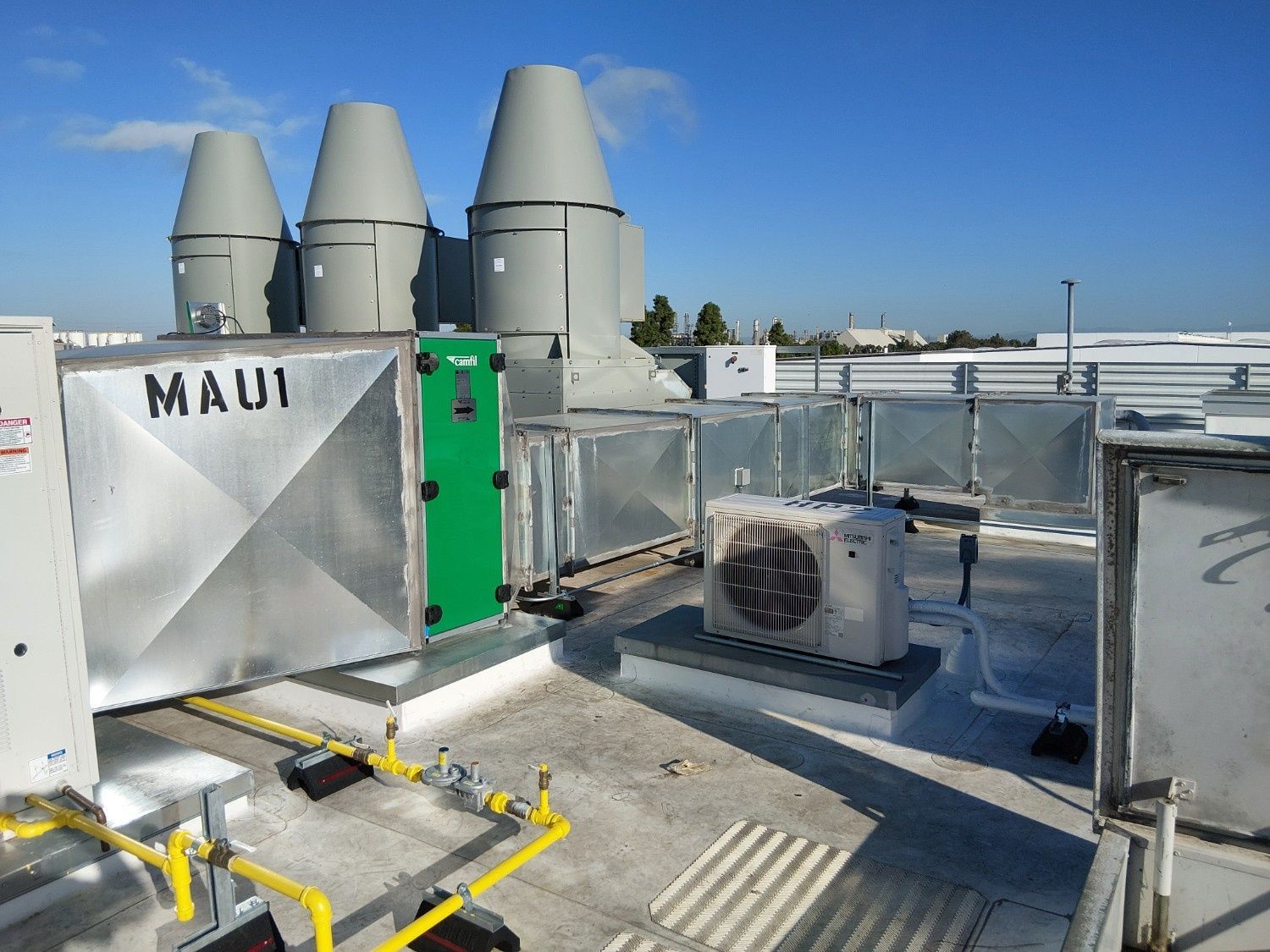 A rooftop view showing large industrial HVAC equipment, metal ductwork labeled 