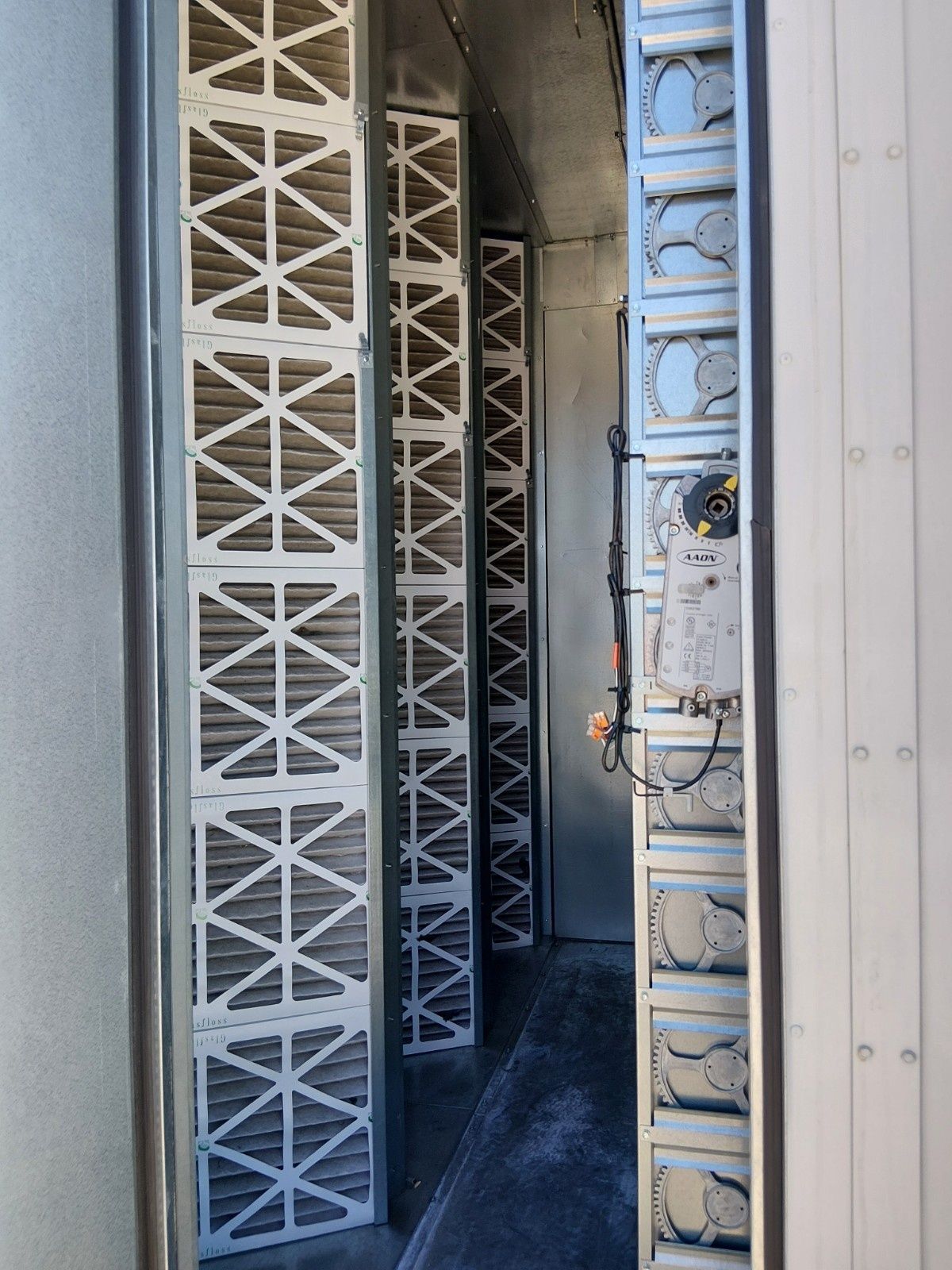 An open HVAC air handler unit interior featuring several rows of installed pleated air filters and metal framing.