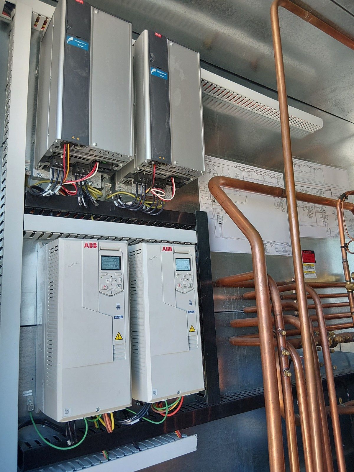 Two ABB variable frequency drives mounted above two matching power supply units in an industrial metal cabinet.