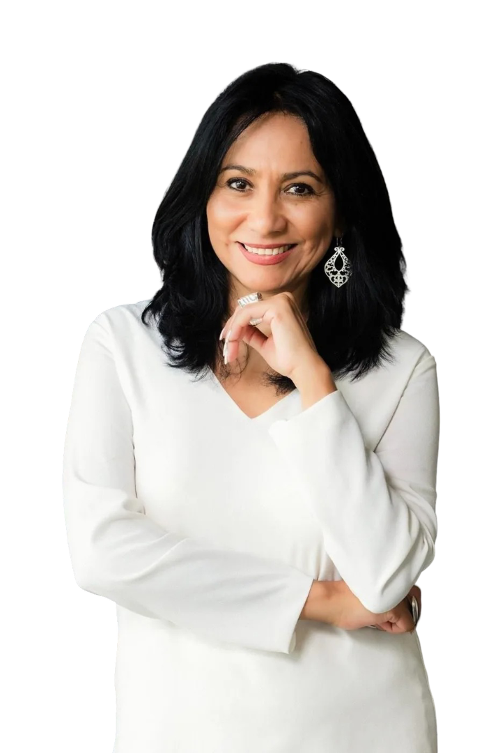 Smiling person with dark hair wearing a white top and dangling earrings, posing with a hand resting on their chin.