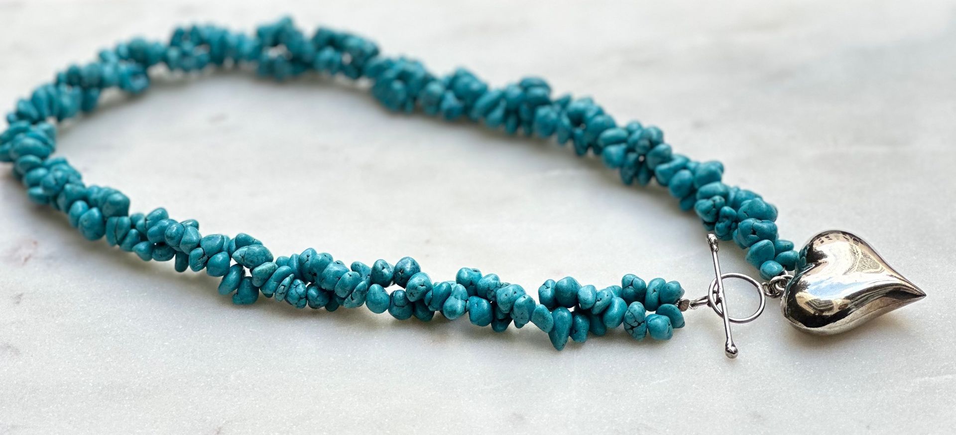 Turquoise bead necklace with a silver heart pendant and toggle clasp.