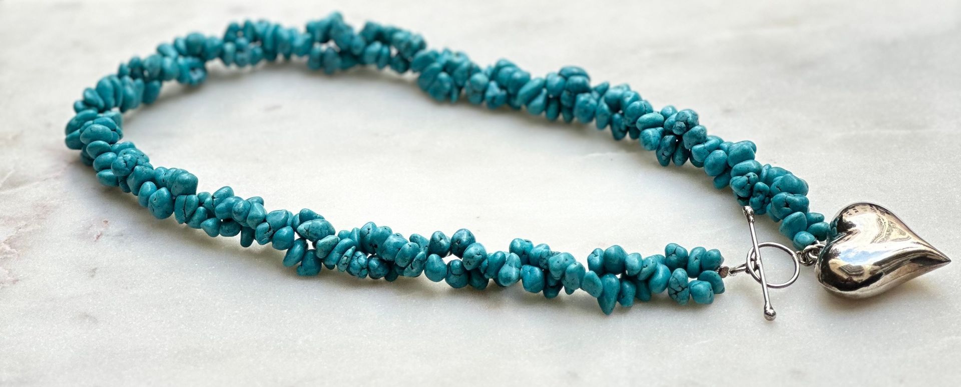 Turquoise bead necklace with a silver heart pendant and toggle clasp.