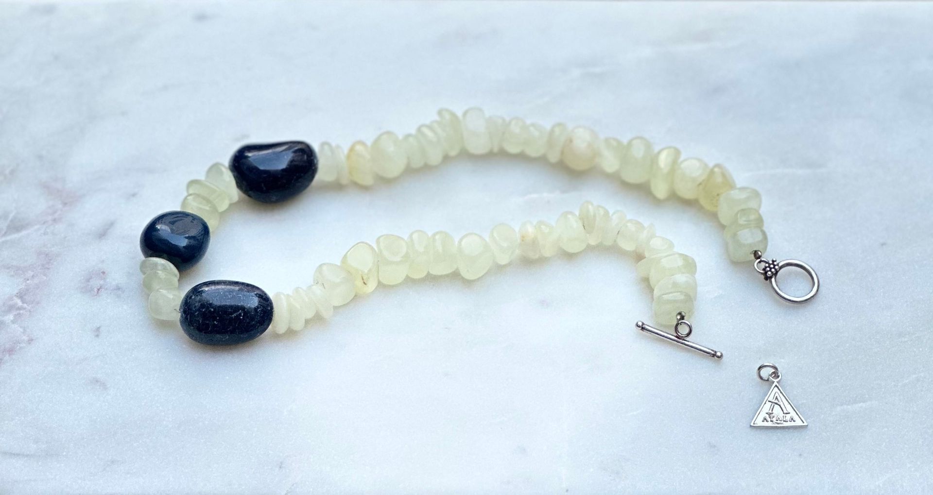 Bracelet with blue and yellow beads, with a silver clasp and a small triangle charm.