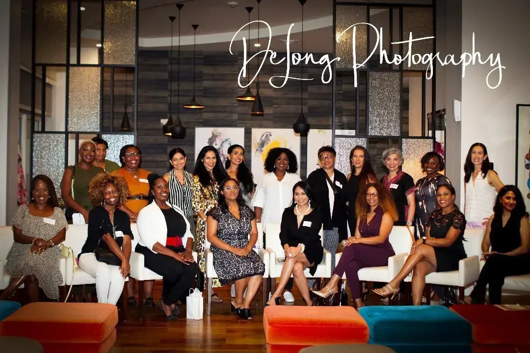 Group of diverse women posing indoors for a photo, with various expressions and attire.