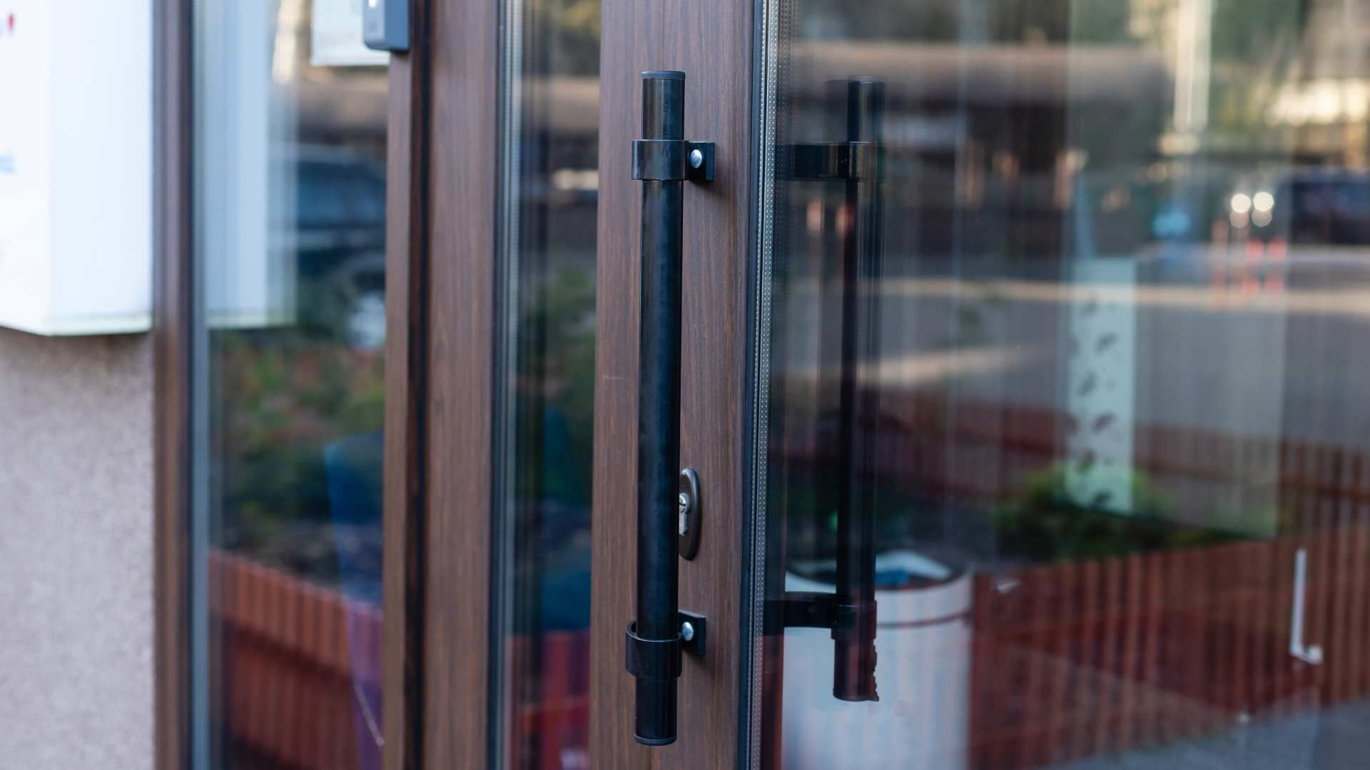 Glass door with black handles and a blurred indoor reflection behind it
