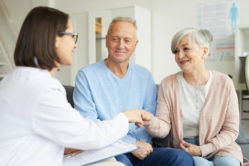 Doctor talking with two patients in a clinic, one holding the other's hand