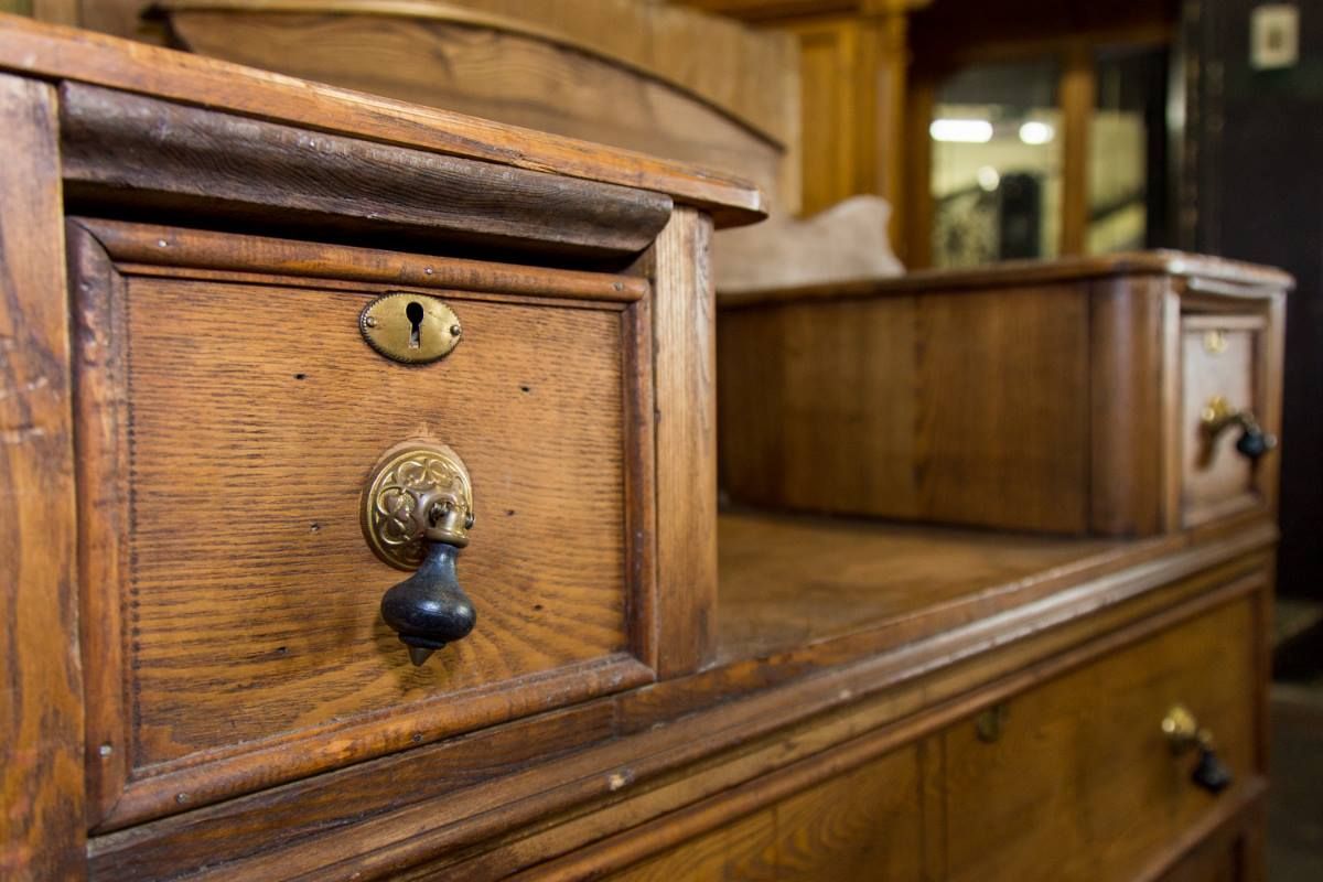 Close-up of antique wooden drawers with brass knobs and warm brown finish.
