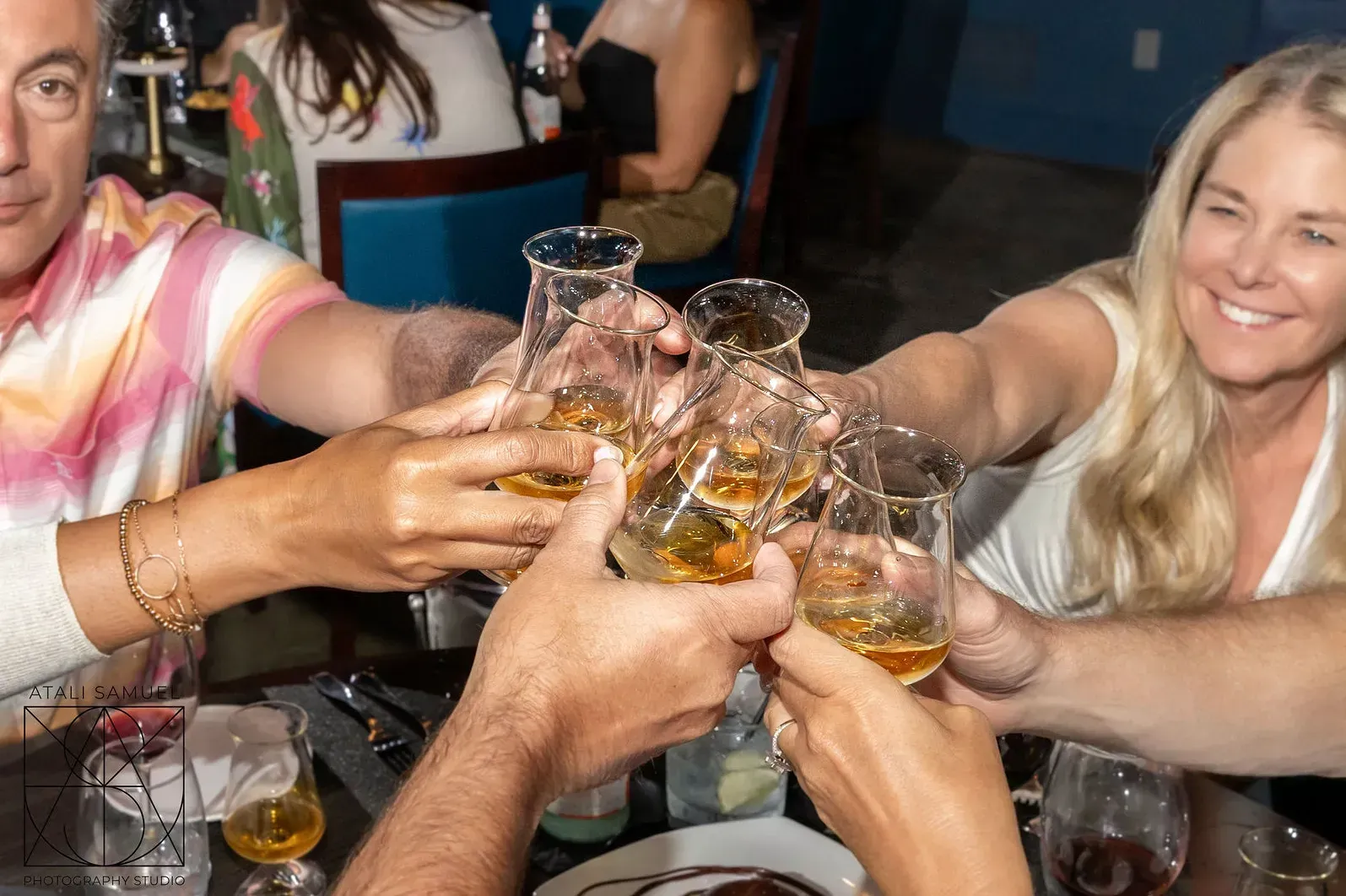 People toasting with glasses of amber liquid at a table.
