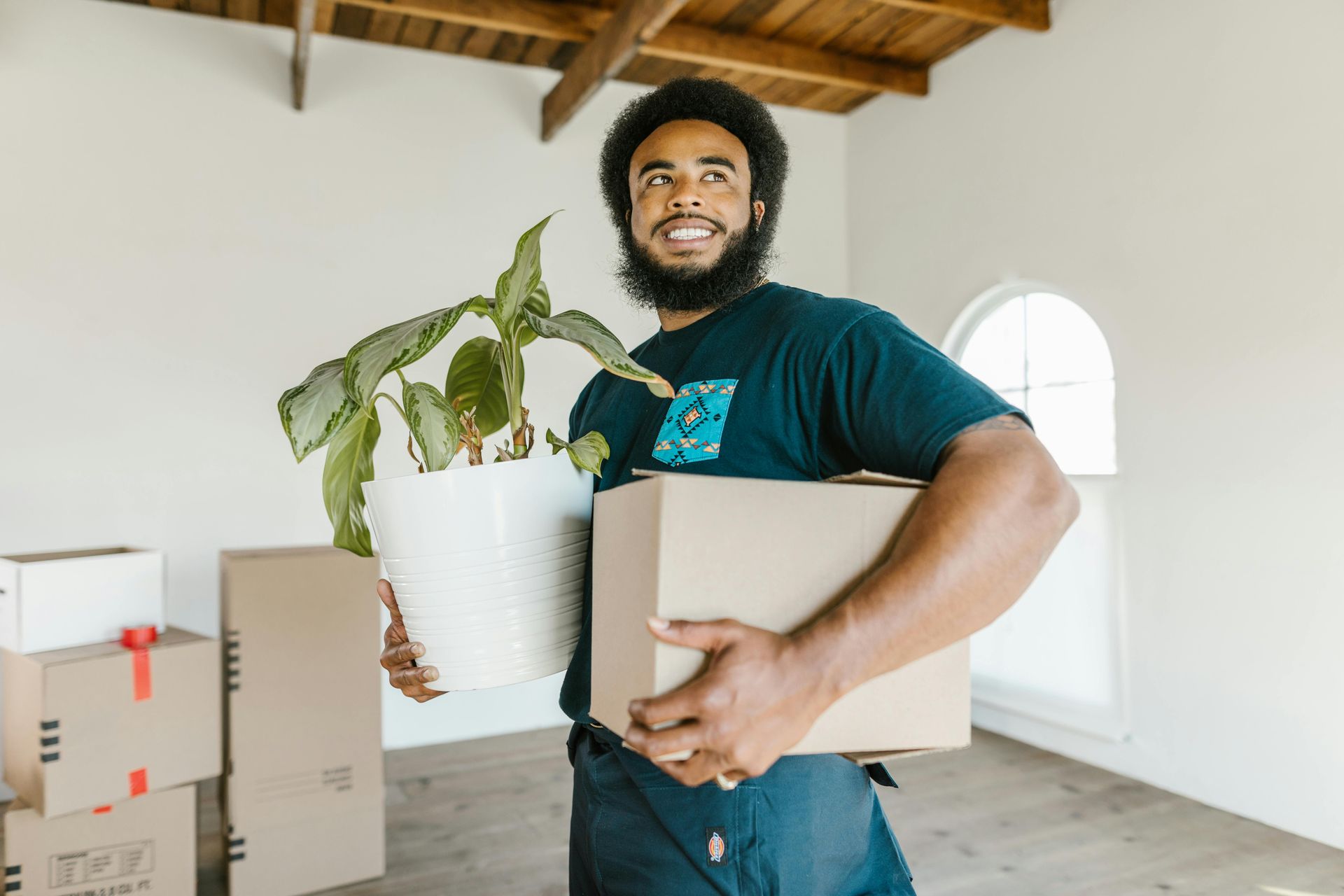 a man holding a cardboard box and a plant in a white pot