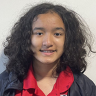 A young girl with long curly hair is smiling for the camera.