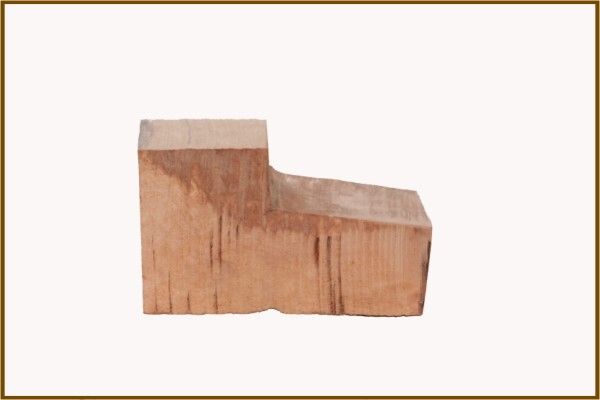 Un pezzo di legno è appoggiato su una superficie bianca.