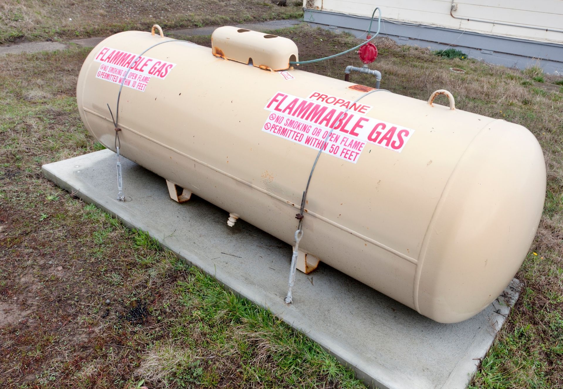 A large propane tank is sitting on top of a concrete platform.