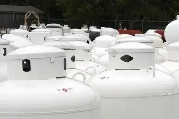 A bunch of white propane tanks are sitting next to each other.