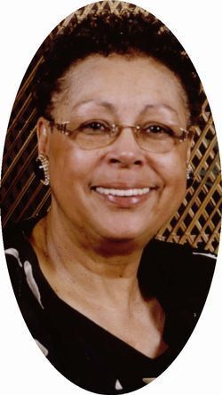 A headshot of a person smiling, wearing glasses and earrings, set against a dark lattice-patterned background.