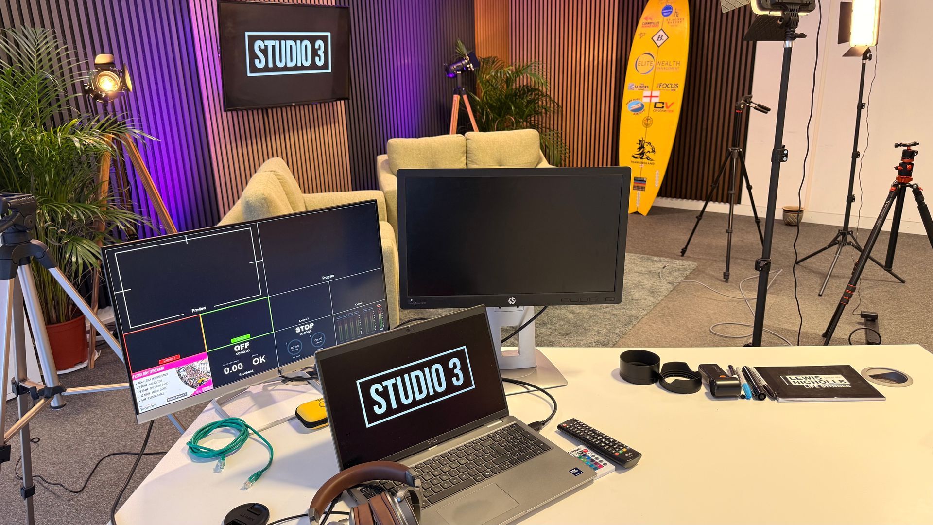 Studio 3 Services' podcast set viewed from the control desk, with chairs, cameras, microphones and coloured lighting.