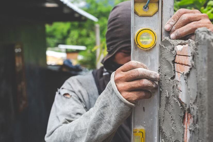 Worker using a level to align a wall during construction