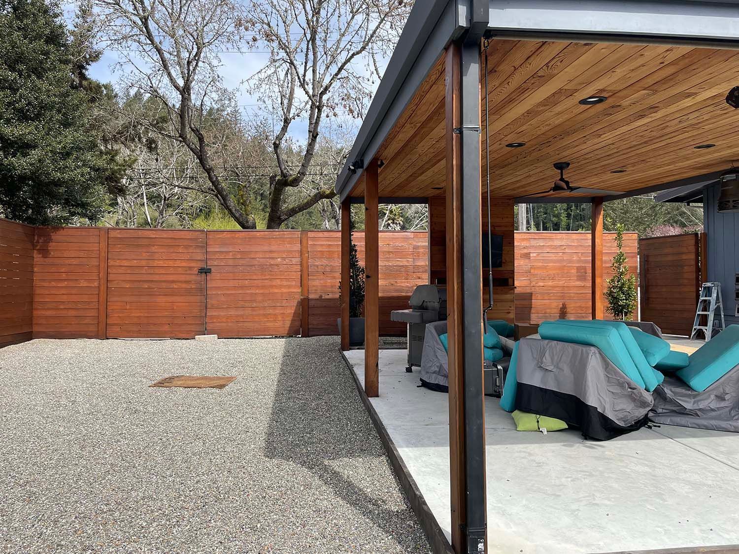 Backyard patio with gravel yard, wooden fence, and covered seating area with outdoor furniture