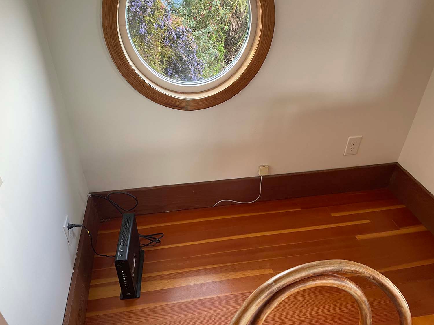 Small room with a round window, wood floor, a heater, and a braided rug edge.