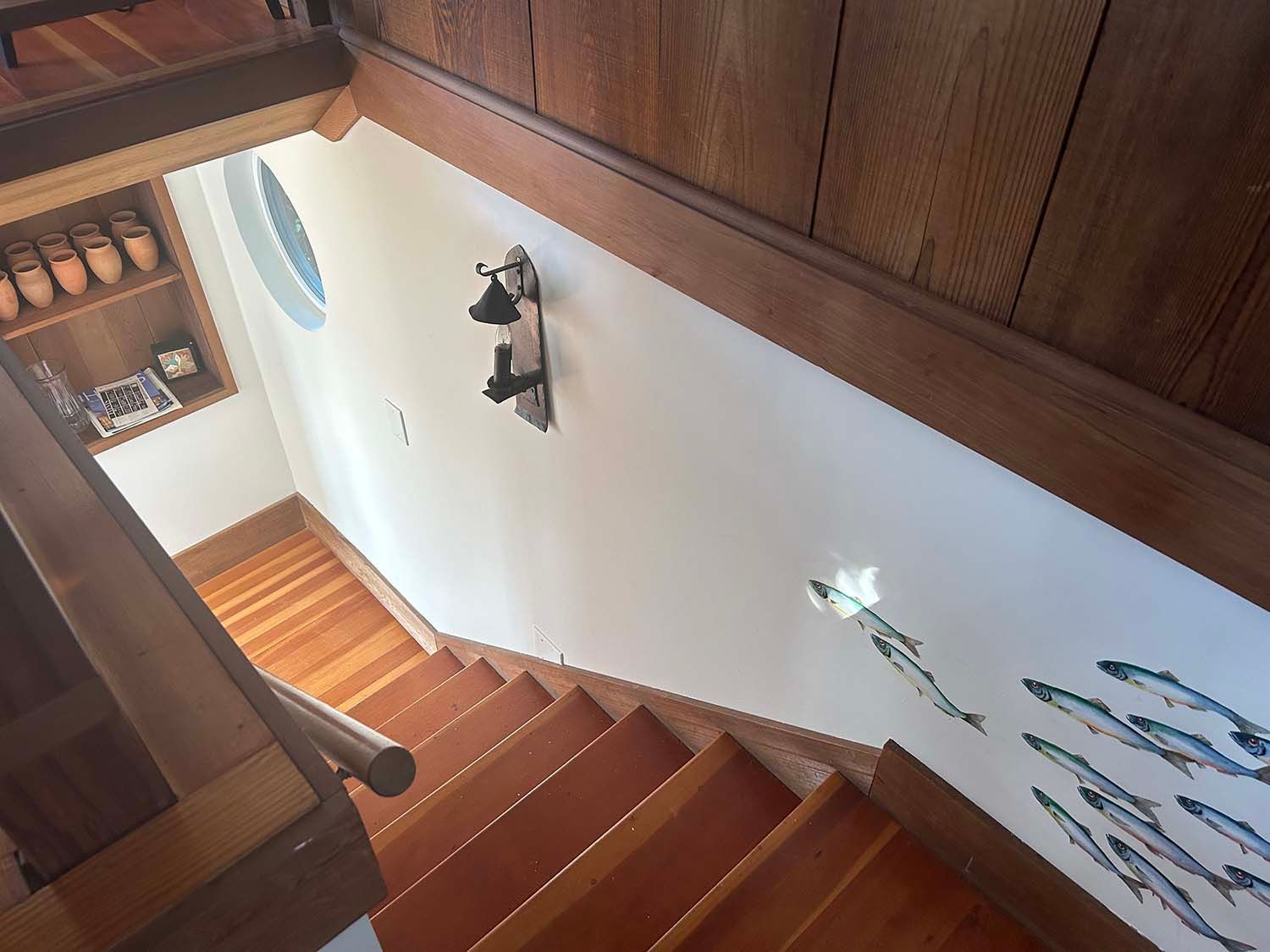 Wooden staircase with white walls and wall art in a bright interior hallway