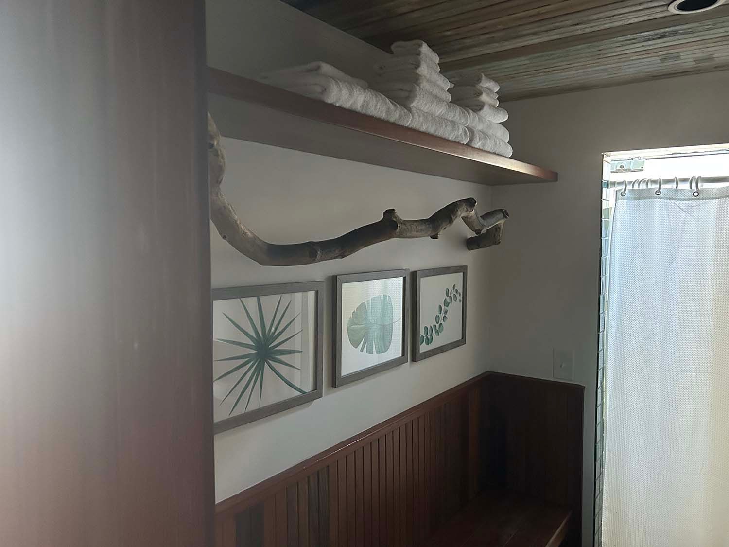 Small room with wood paneling, wall art, driftwood shelf, and a curtained window.