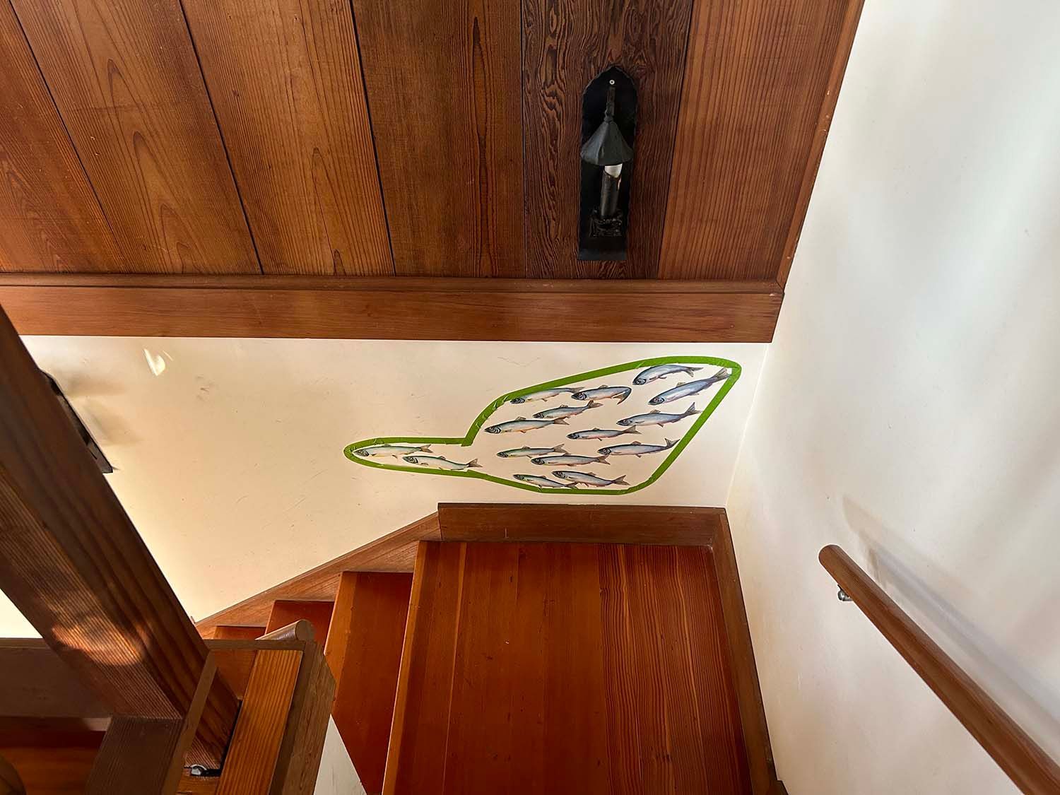 Stairwell with wood paneling and a wall mural outlined in green on the landing.