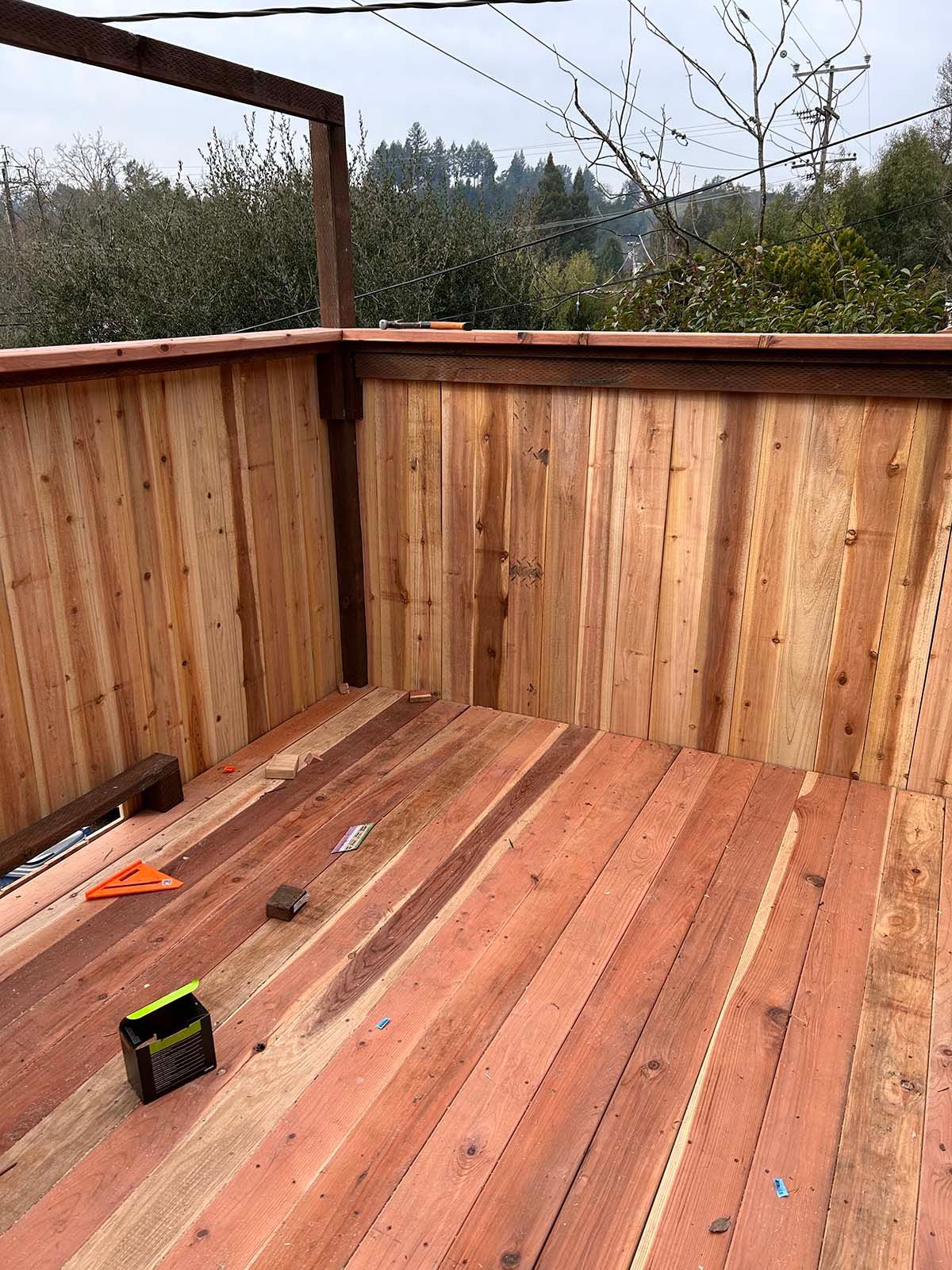 Wooden deck under construction with partially built railing and tools on the floor