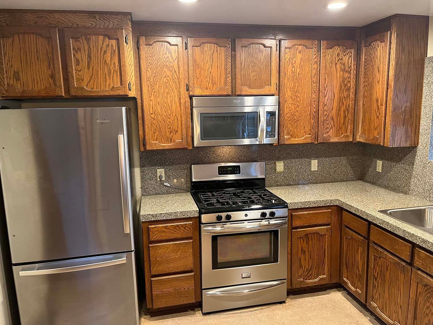 Modern kitchen with wood cabinets, stainless steel appliances, granite countertops, and tile backsplash