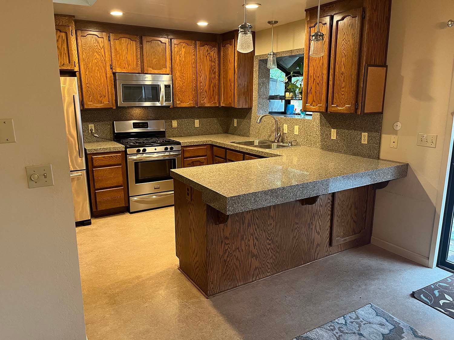 Kitchen with wood cabinets, granite countertops, stainless steel stove, and a breakfast bar peninsula.