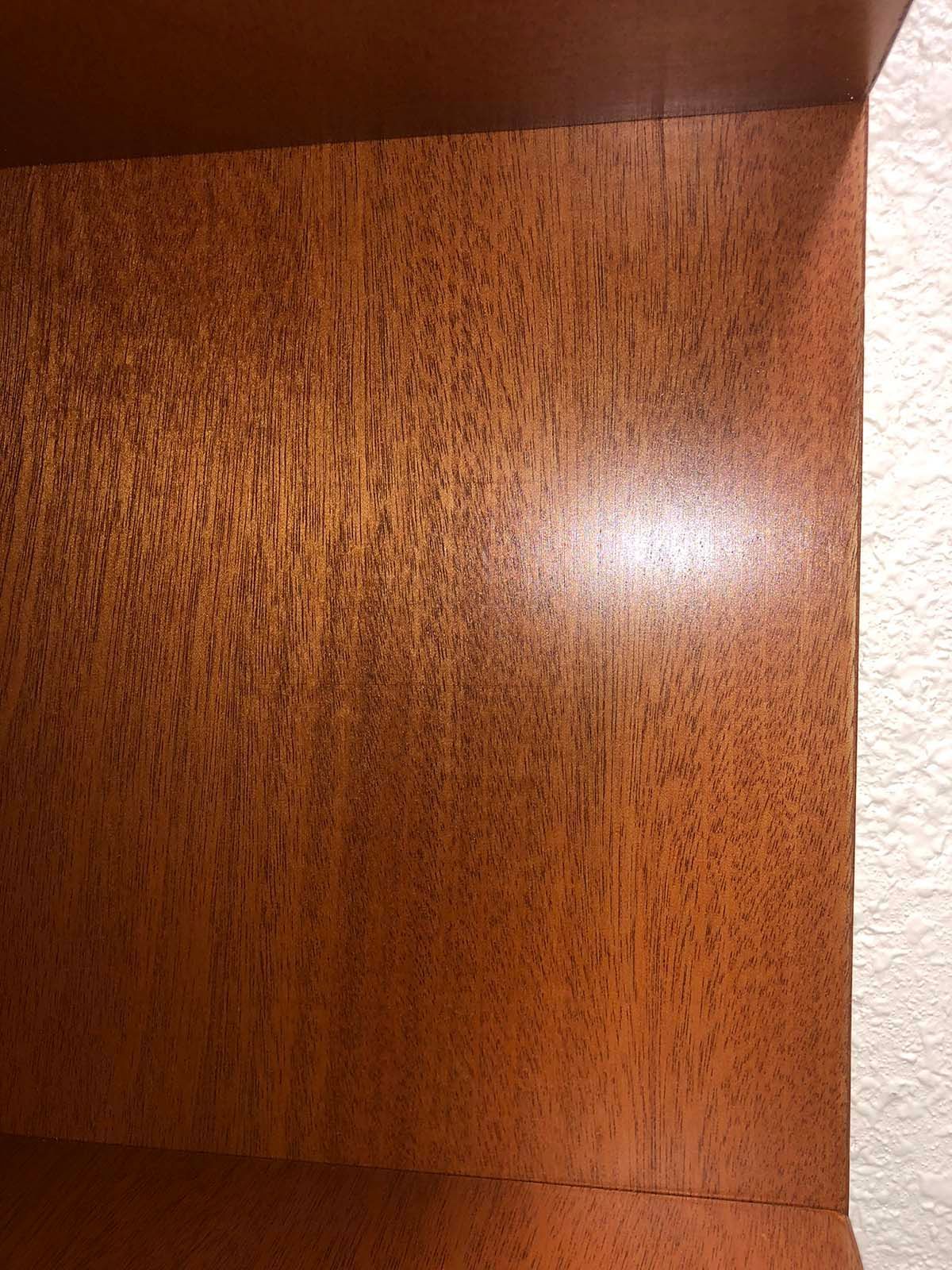 Wood-grain wooden cabinet interior with a bright light reflection on the back panel